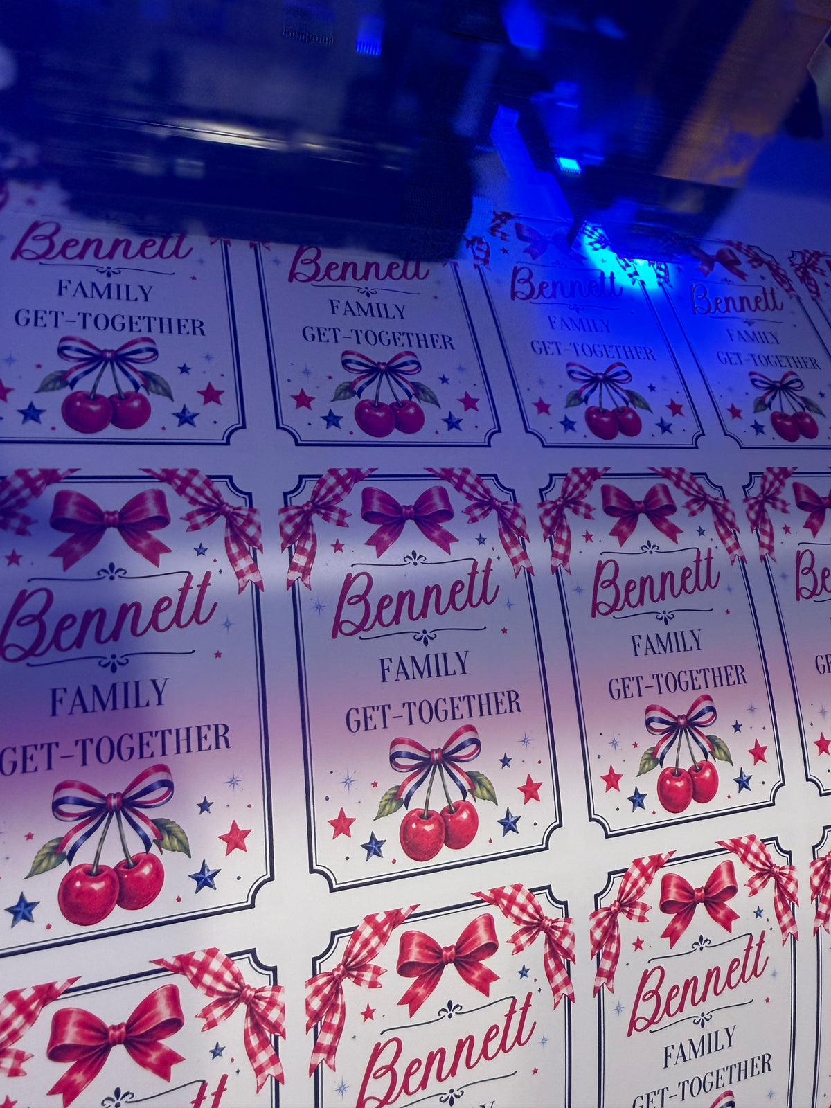 Bennett family get-together stickers with cherries, bows and stars being printed under blue UV light.