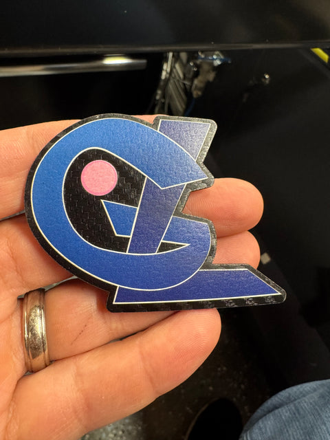 Blue geometric logo patch with a pink dot held in a hand