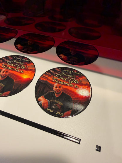 Round memorial photo stickers with a portrait and orange sunset background, printed in rows on white vinyl.