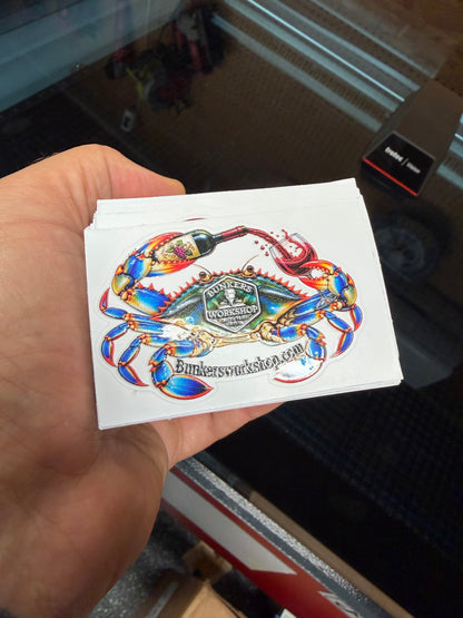 Close-up of a Bunkers Workshop crab logo sticker with spot-gloss texture, held in a hand.