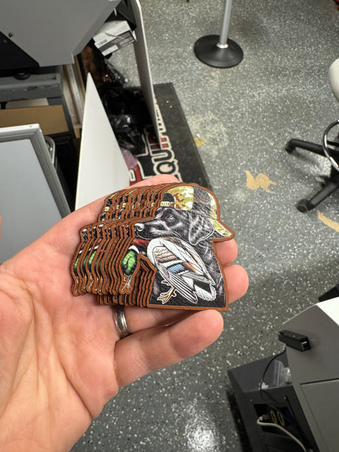 Stack of full-color illustrated patches with custom-cut edges held in a hand