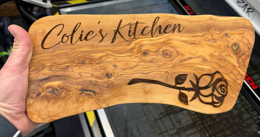Custom laser engraving service example: Colie's Kitchen design and rose engraved on an olive-wood cutting board.