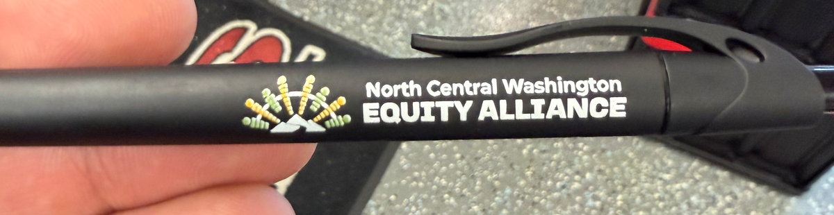Close-up of a black pen with North Central Washington Equity Alliance printed branding.